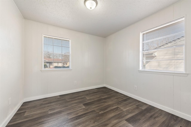 empty room featuring dark wood-style floors, a textured ceiling, and baseboards