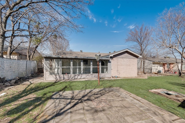 back of property with a lawn, a sunroom, fence, a patio area, and brick siding