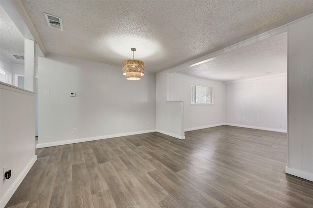 empty room with baseboards, a textured ceiling, visible vents, and wood finished floors