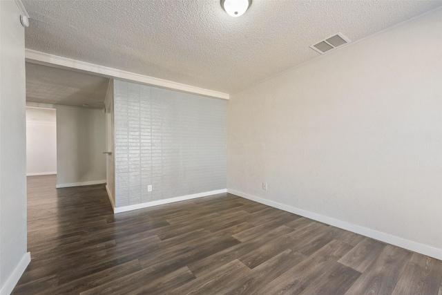 spare room featuring visible vents, dark wood finished floors, and a textured ceiling