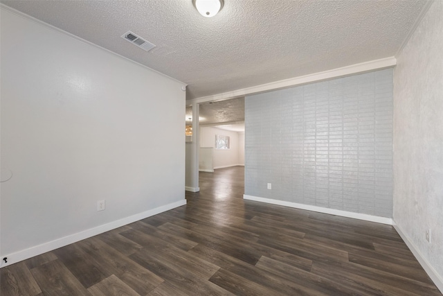 empty room featuring baseboards, visible vents, dark wood finished floors, crown molding, and a textured ceiling