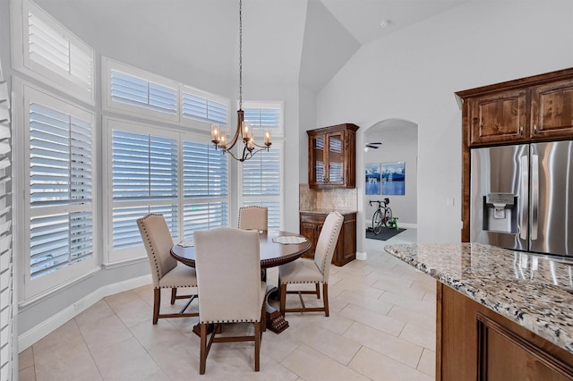 tiled dining room with an inviting chandelier and high vaulted ceiling