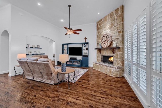 living room featuring ornamental molding, a stone fireplace, and dark hardwood / wood-style flooring