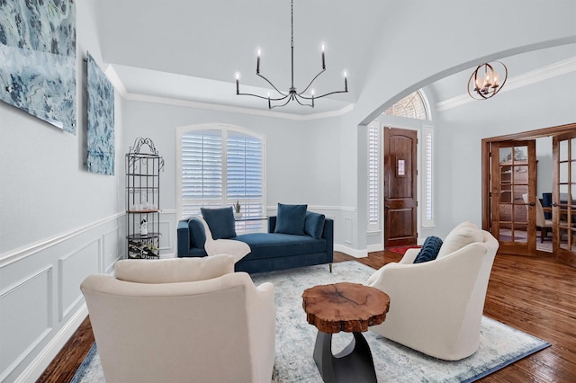 living room featuring crown molding, wood-type flooring, and an inviting chandelier