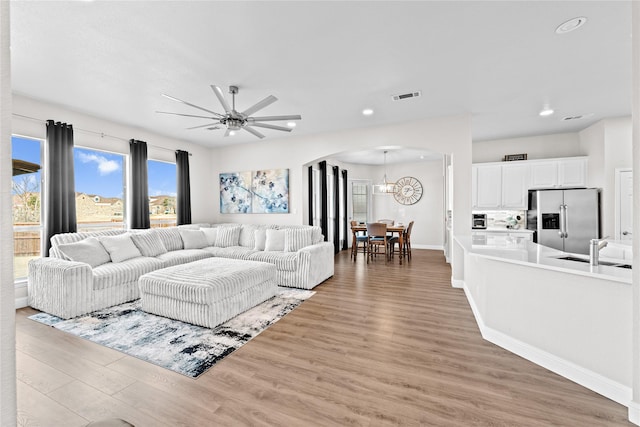 living room featuring hardwood / wood-style flooring, sink, and ceiling fan