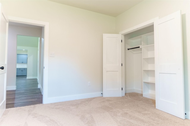 unfurnished bedroom with light carpet and a closet