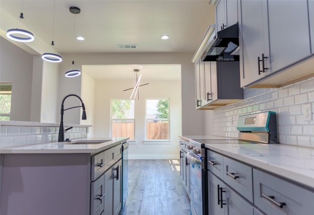 kitchen with appliances with stainless steel finishes, pendant lighting, sink, gray cabinetry, and light stone counters