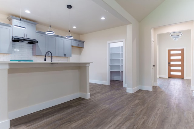 kitchen featuring sink, decorative light fixtures, vaulted ceiling, dark hardwood / wood-style flooring, and decorative backsplash