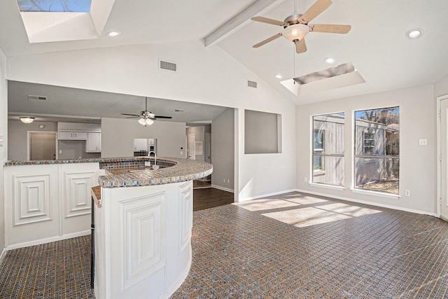 kitchen with beamed ceiling, white cabinets, fridge, ceiling fan, and dark carpet