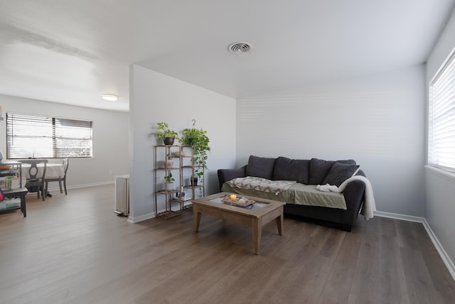 living room with plenty of natural light and dark wood-type flooring