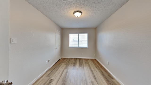 unfurnished room featuring a textured ceiling and light wood-type flooring