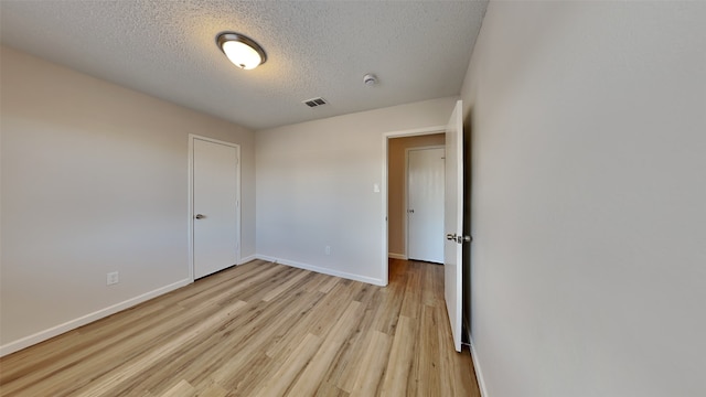 unfurnished bedroom featuring a textured ceiling and light hardwood / wood-style flooring