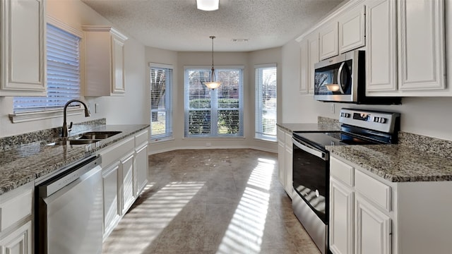 kitchen with hanging light fixtures, white cabinetry, appliances with stainless steel finishes, and sink