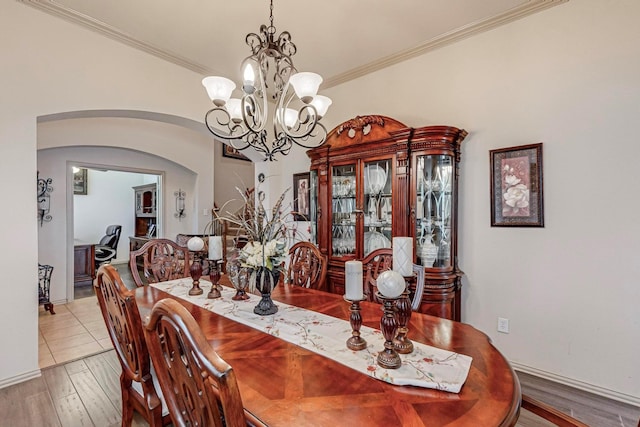 dining space with ornamental molding, a notable chandelier, and light hardwood / wood-style flooring