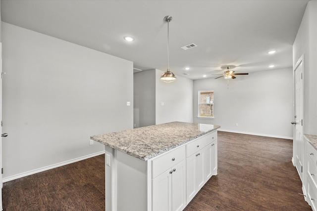 kitchen with white cabinetry, pendant lighting, light stone countertops, and a kitchen island