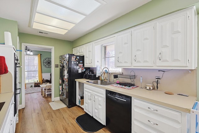 kitchen with sink, white cabinets, light hardwood / wood-style floors, and black appliances