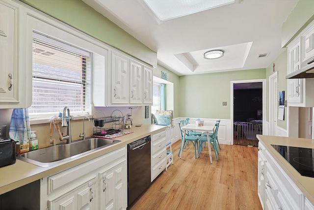 kitchen with sink, light hardwood / wood-style flooring, a tray ceiling, black appliances, and white cabinets