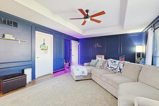 living room featuring a tray ceiling, wood-type flooring, and ceiling fan