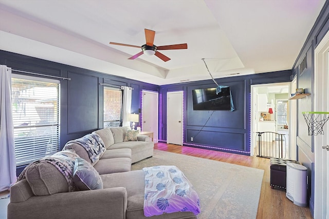 living room featuring hardwood / wood-style floors, a raised ceiling, and ceiling fan