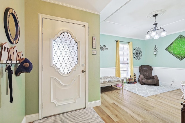 foyer with crown molding, hardwood / wood-style floors, and a notable chandelier