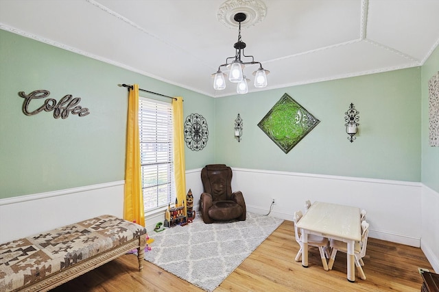 sitting room with hardwood / wood-style flooring, ornamental molding, and a chandelier