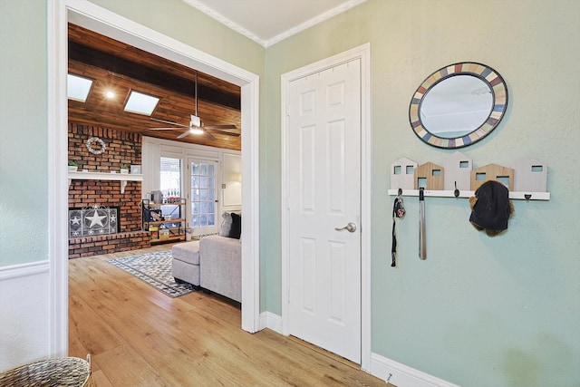 corridor with ornamental molding, wood ceiling, and light wood-type flooring