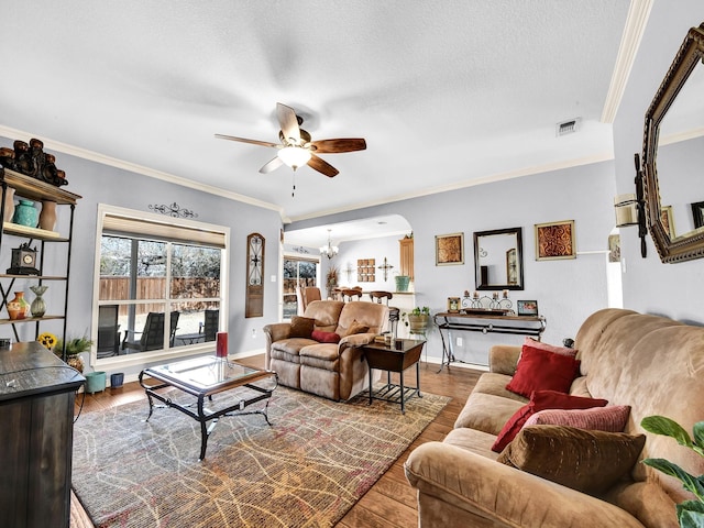 living room with ceiling fan with notable chandelier, ornamental molding, hardwood / wood-style floors, and a textured ceiling