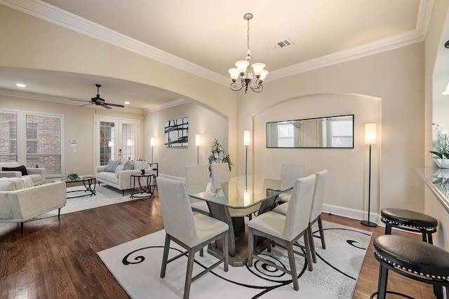 dining space featuring crown molding, dark wood-type flooring, and ceiling fan with notable chandelier