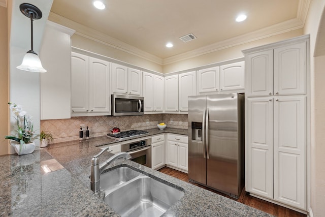 kitchen featuring sink, hanging light fixtures, appliances with stainless steel finishes, white cabinets, and backsplash