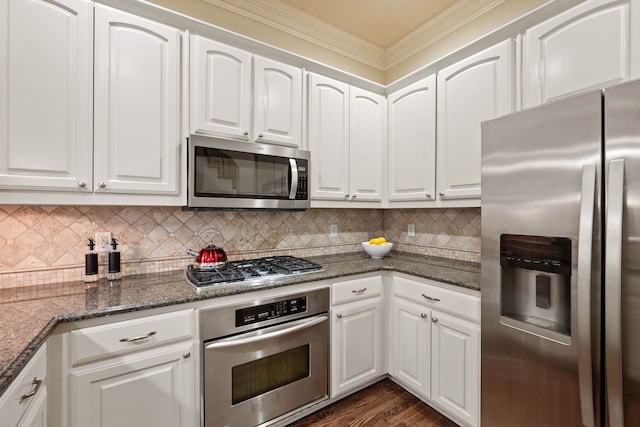 kitchen with tasteful backsplash, dark stone countertops, appliances with stainless steel finishes, dark hardwood / wood-style floors, and white cabinets