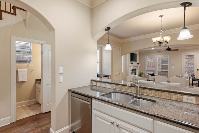 kitchen featuring pendant lighting, sink, dark stone countertops, and dishwasher