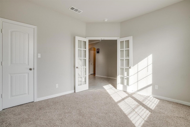 spare room featuring light carpet and french doors