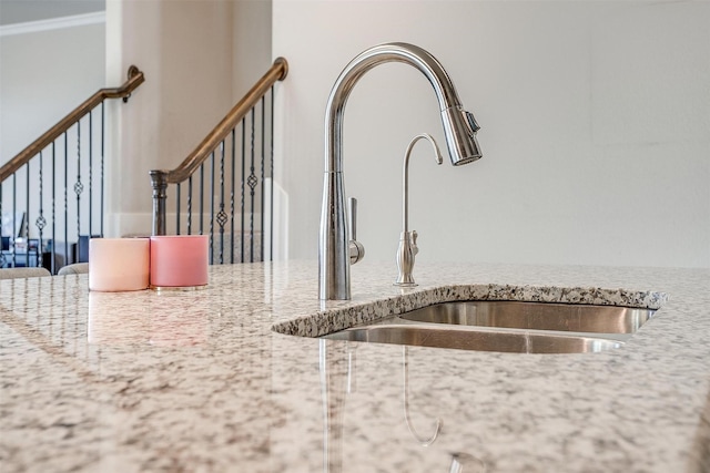 interior details with crown molding, light stone countertops, and sink