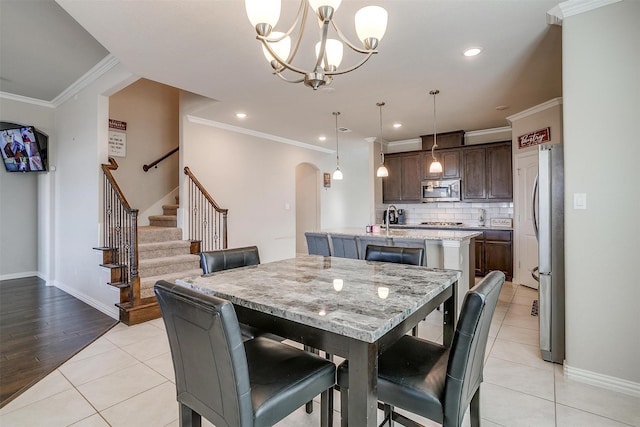 dining room featuring crown molding, a notable chandelier, sink, and light tile patterned floors