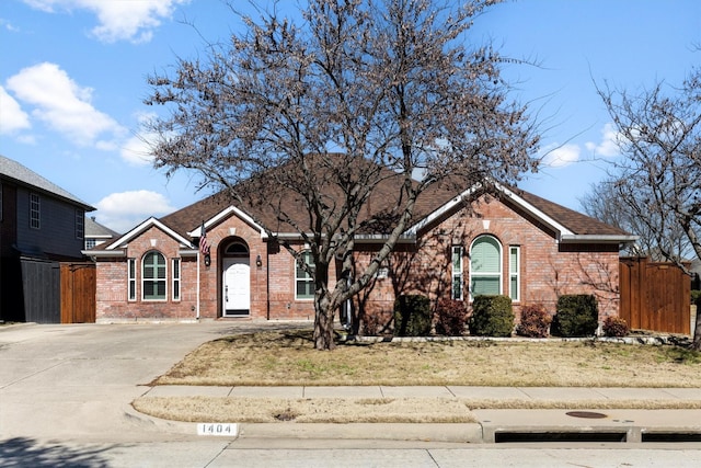 ranch-style house featuring concrete driveway, fence, and brick siding