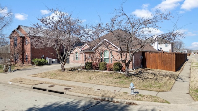 view of front of home with brick siding, cooling unit, and fence