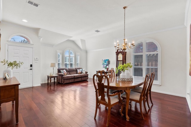 dining area with dark hardwood / wood-style floors, vaulted ceiling, and a notable chandelier