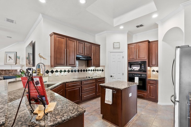 kitchen featuring sink, a center island, tasteful backsplash, black appliances, and dark stone counters