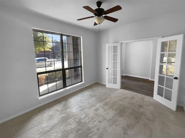 empty room with ceiling fan, dark carpet, and french doors