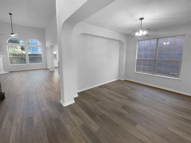 unfurnished dining area with ceiling fan with notable chandelier and dark wood-type flooring