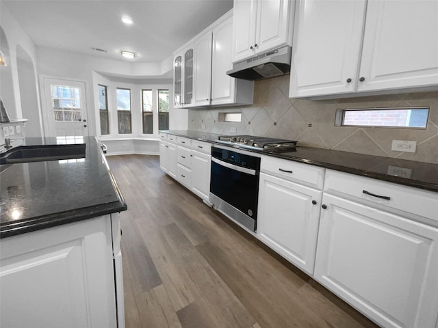 kitchen featuring stainless steel gas cooktop, white cabinetry, dark hardwood / wood-style flooring, oven, and backsplash