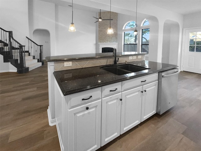 kitchen featuring sink, decorative light fixtures, stainless steel dishwasher, an island with sink, and white cabinets