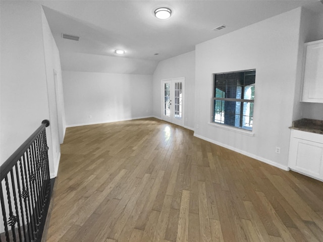 unfurnished living room featuring hardwood / wood-style flooring, lofted ceiling, and french doors