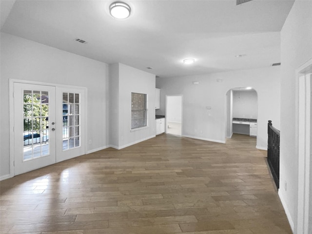 unfurnished living room featuring dark hardwood / wood-style flooring and french doors