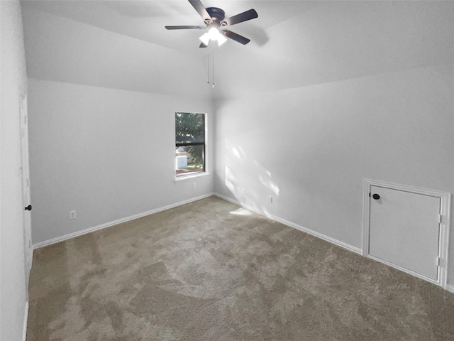 carpeted spare room featuring vaulted ceiling and ceiling fan