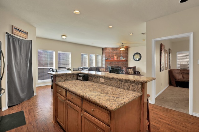 kitchen featuring a fireplace, a kitchen breakfast bar, a center island, and dark hardwood / wood-style flooring