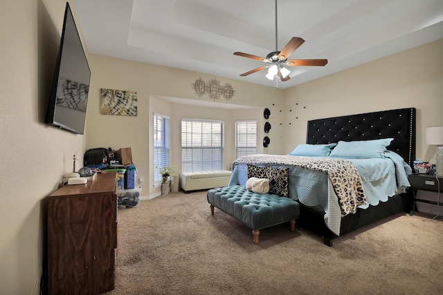 bedroom featuring ceiling fan, a raised ceiling, and light carpet