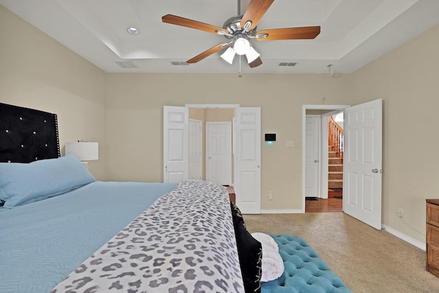 bedroom featuring ceiling fan, a raised ceiling, and carpet