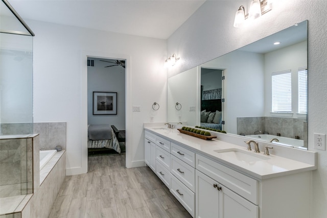 bathroom with vanity, a relaxing tiled tub, and wood-type flooring