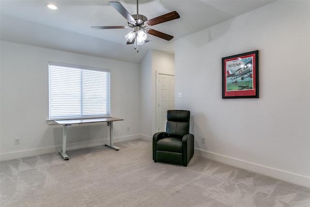 living area featuring light carpet and ceiling fan